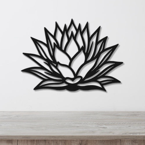 Black metal agave wall sculpture with layered leaf cutouts, mounted on a white wall above a light wood counter.