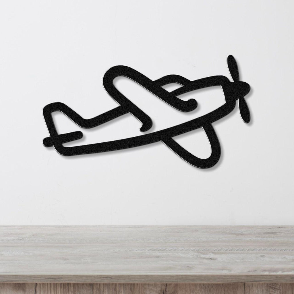 Black metal airplane wall art with a silhouette design, mounted on a white wall above a light wood surface.