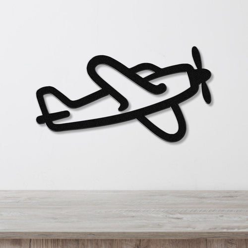 Black metal airplane wall art with a silhouette design, mounted on a white wall above a light wood surface.