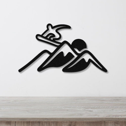 Black metal wall art silhouette of a snowboarder on a mountain, mounted on a white wall above a wooden counter.