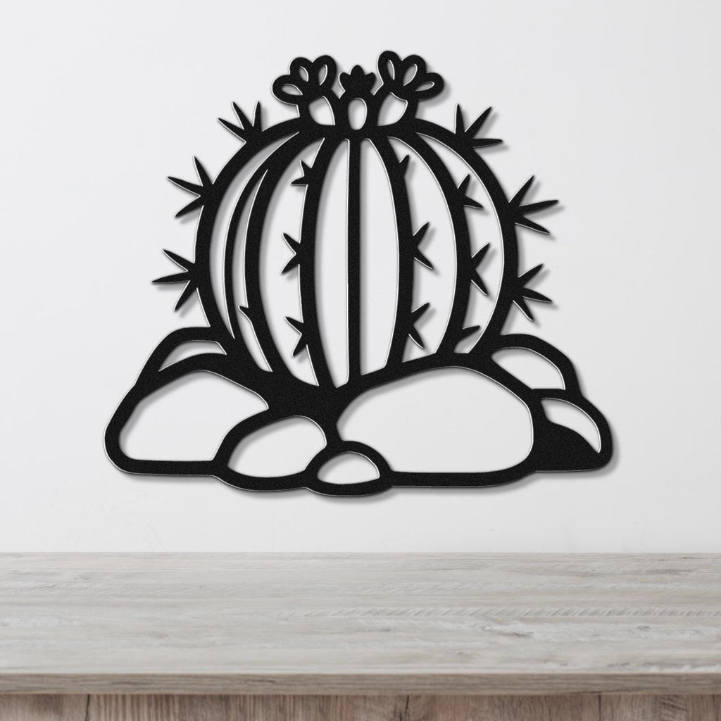 Black metal barrel cactus wall art with flower and spine cutouts, mounted on a white wall above a wooden counter.