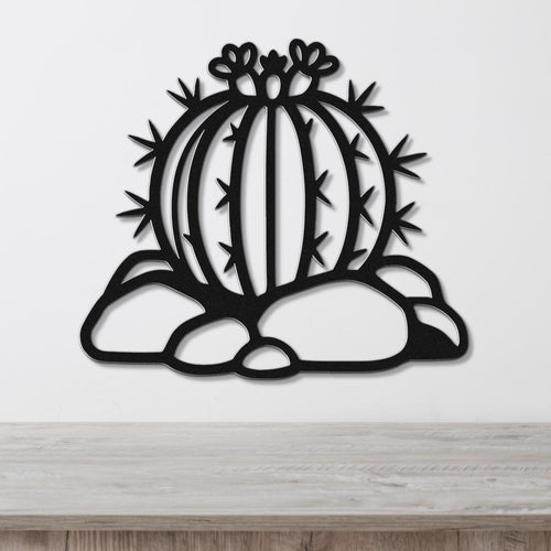 Black metal barrel cactus wall art with flower and spine cutouts, mounted on a white wall above a wooden counter.