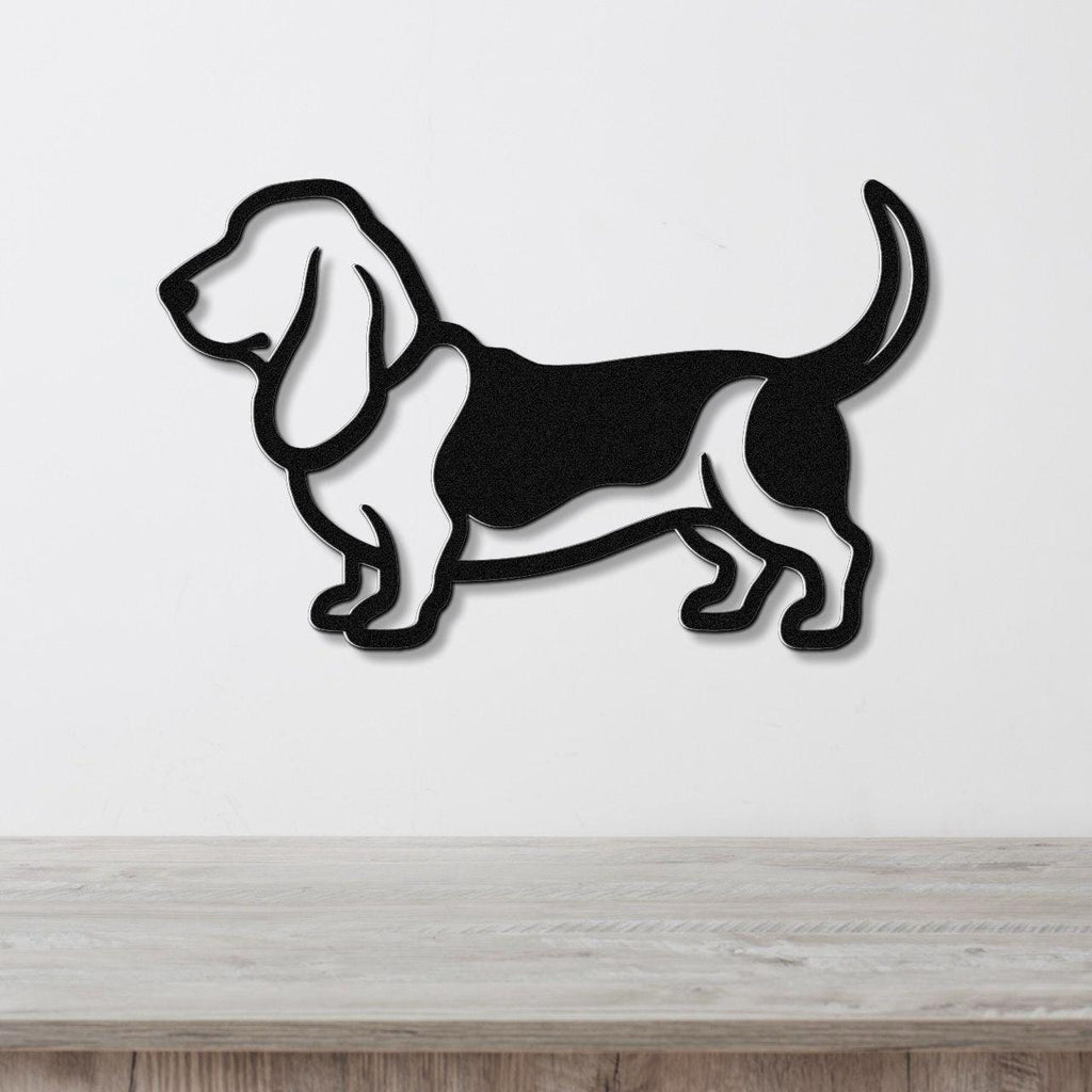 Black metal wall art silhouette of a basset hound, mounted on a white wall above a light wood surface.