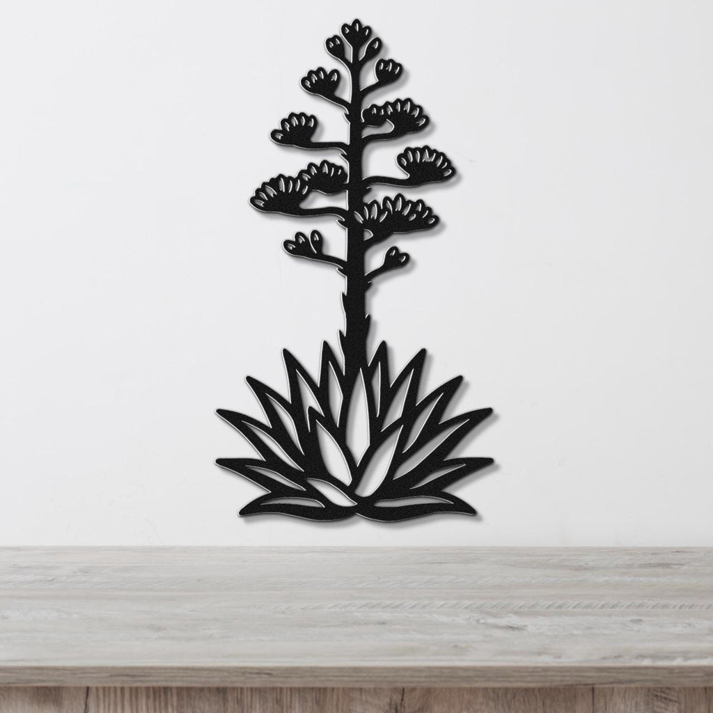 Black metal agave wall sculpture with blooming flower cutouts, mounted on a white wall above a light wood counter.