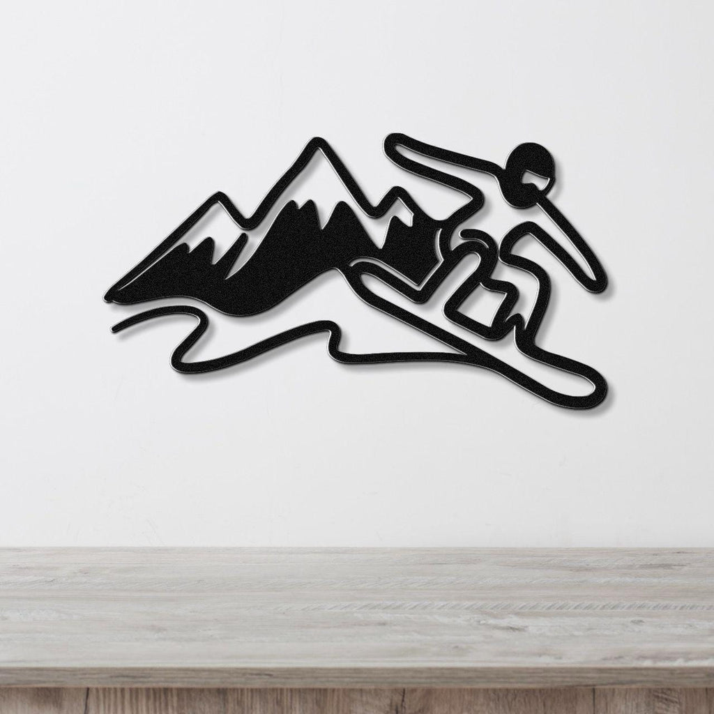 Black metal wall art silhouette of a snowboarder in motion above a wooden counter, with mountain peaks and powder trails cut out from the design.