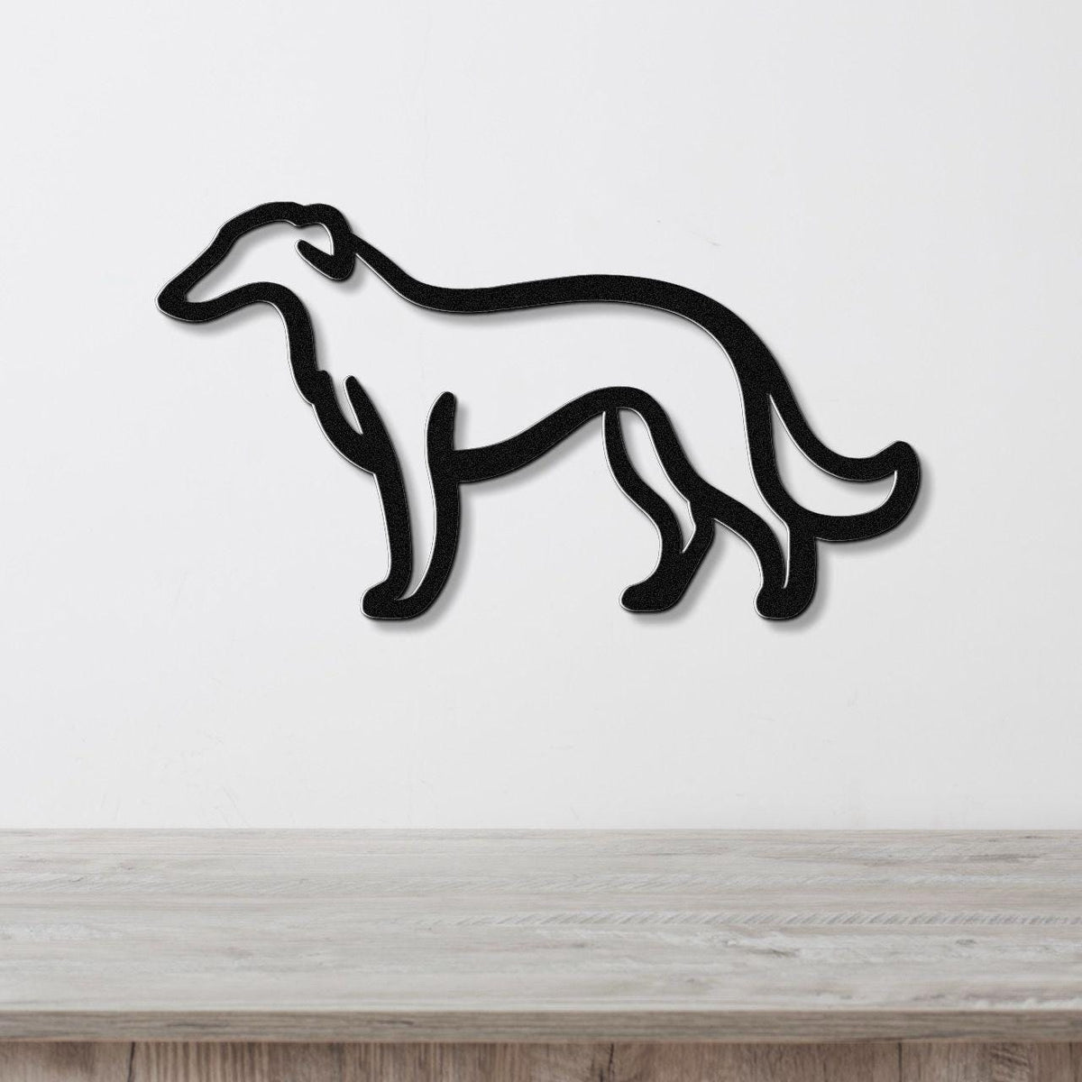 Black metal wall art in the silhouette of a Borzoi dog, mounted on a white wall above a light wood surface.