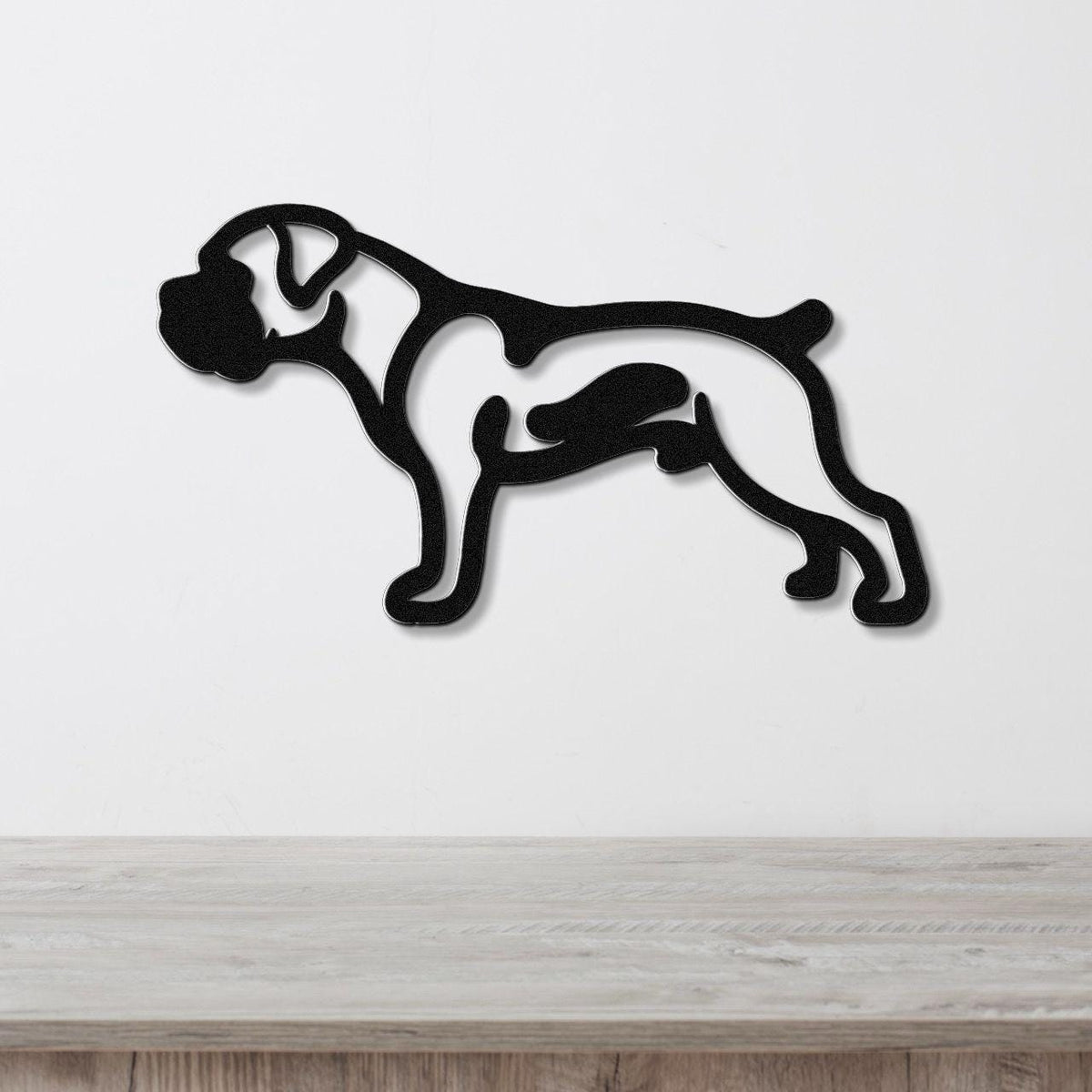 Black metal Boxer dog wall art in silhouette cutout style, mounted on a white wall above a light wood surface.