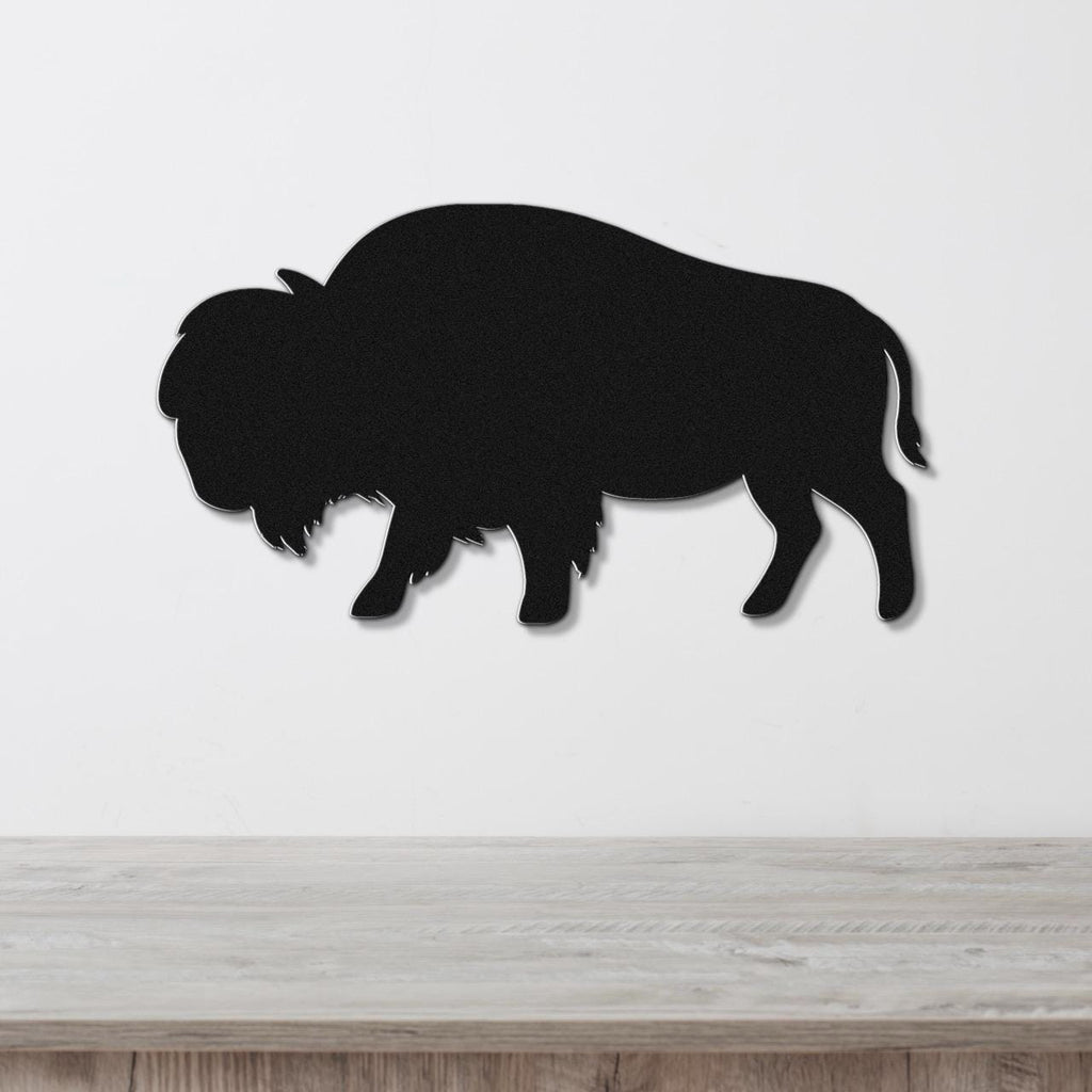 Black metal buffalo silhouette wall art, mounted on a white wall above a light wood countertop.