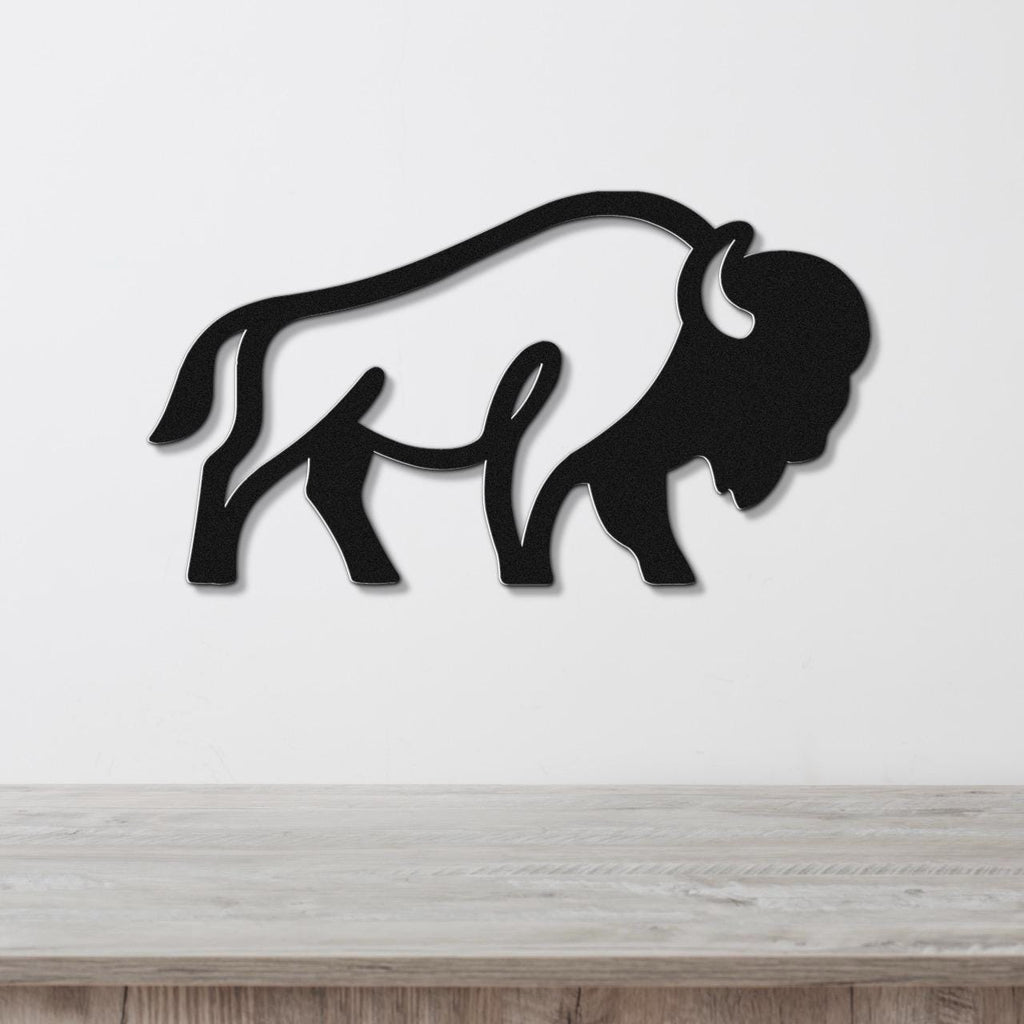 Black metal bison silhouette wall art with cutout horns and tail, mounted on a white wall above a light wood counter.