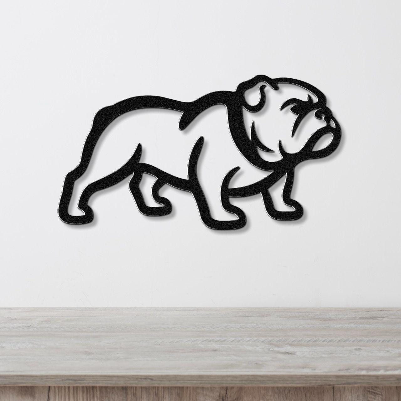 Black metal bulldog wall art with a bold silhouette cutout, mounted on a white wall above a light wood surface.