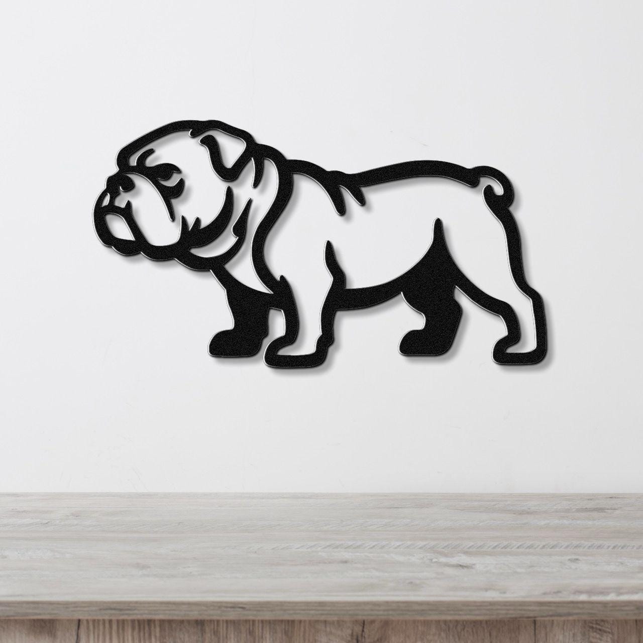 Black metal bulldog wall art with a cutout silhouette design, mounted on a white wall above a light wood surface.