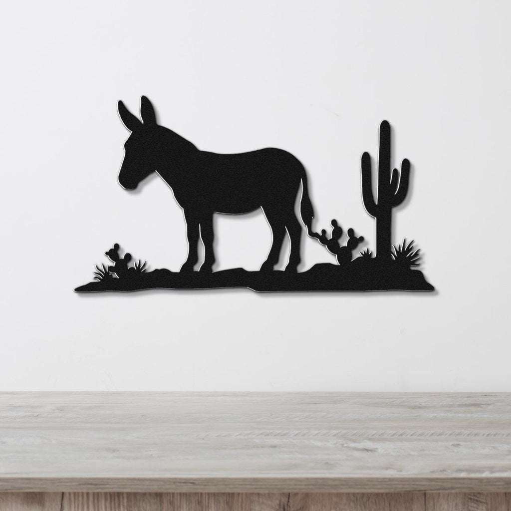 Black metal wall art silhouette of a burro and cacti, mounted on a white wall above a wooden surface.
