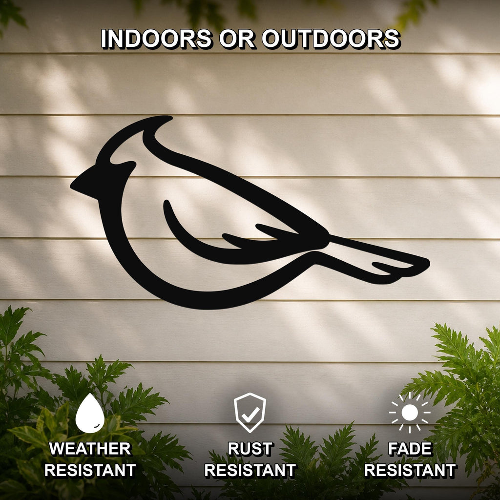 Black metal cardinal wall art silhouette mounted on a beige outdoor wall, with green plants at the base and text indicating it is weather, rust, and fade resistant.