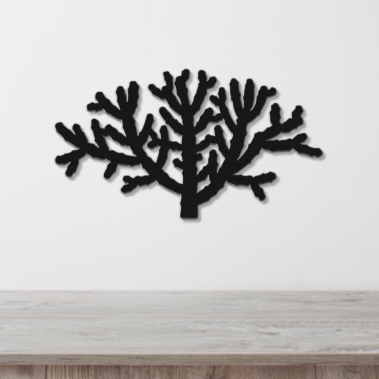 Black metal wall art in a cholla cactus silhouette with branching cutouts, mounted on a white wall above a light wood counter.