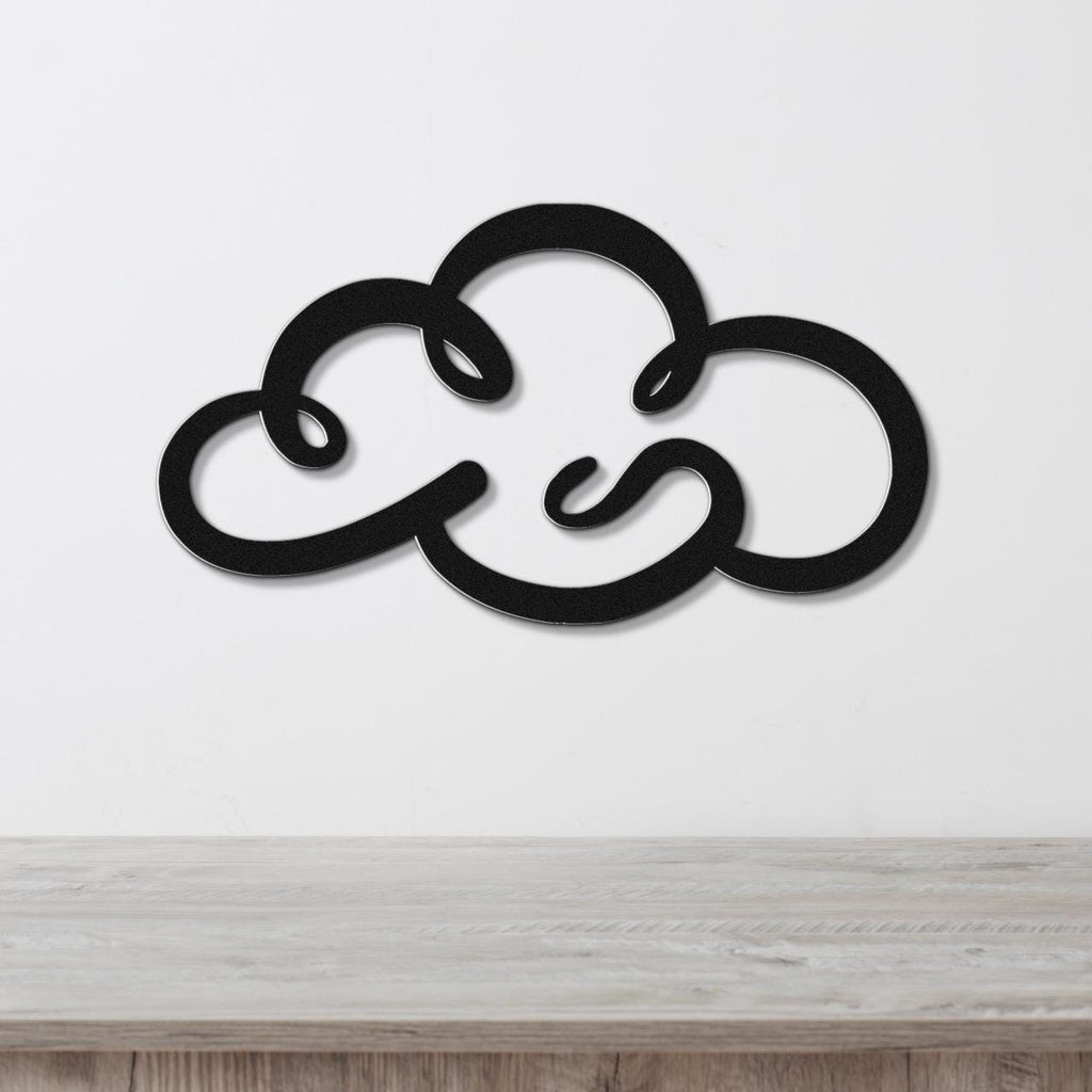Black metal cloud wall art with a cutout design, mounted on a white wall above a light wood surface.