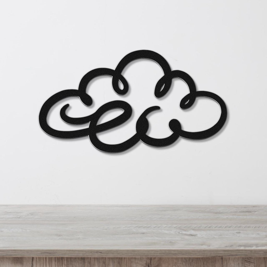 Black metal cloud wall art with flowing silhouette cutouts, mounted on a white wall above a light wood surface.