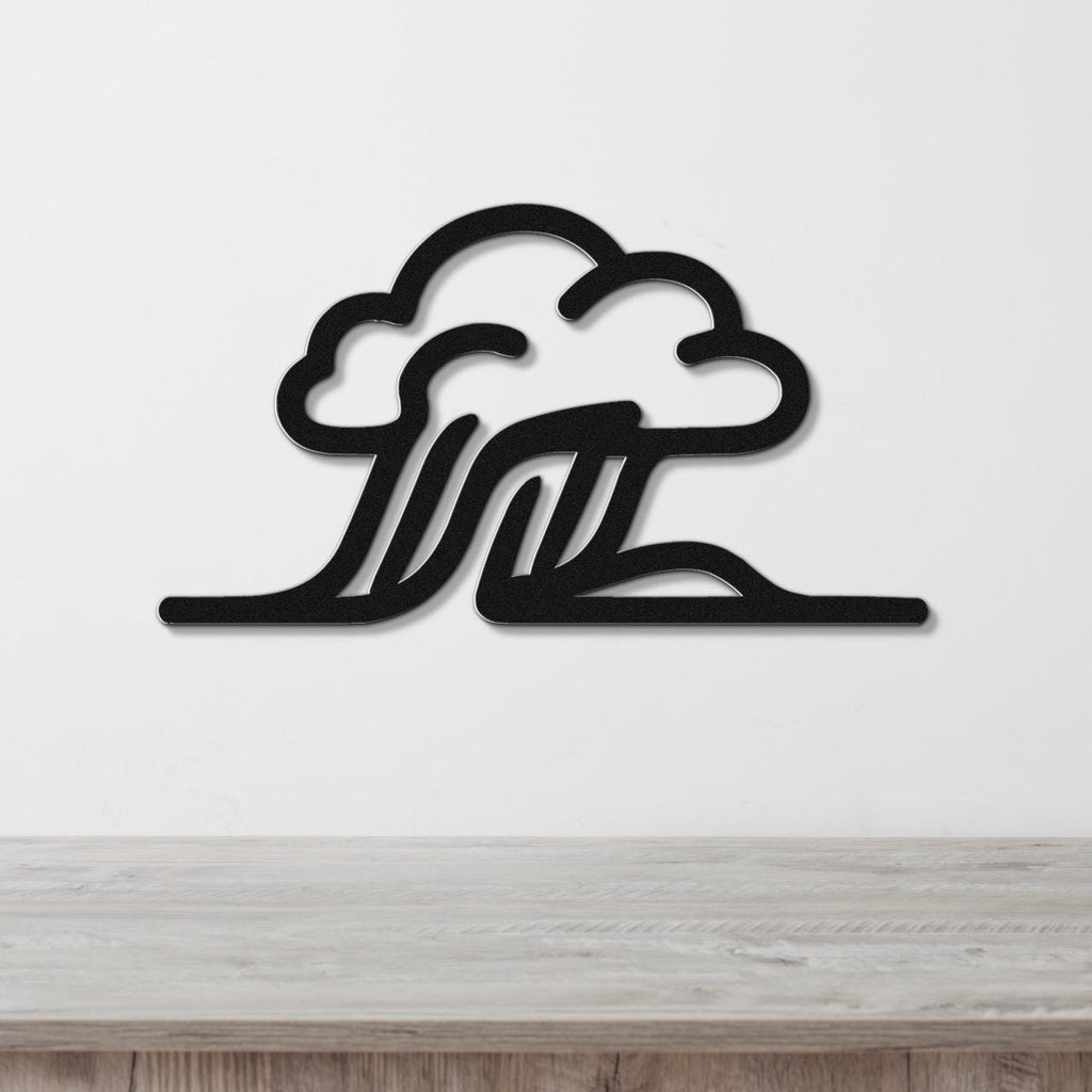 Black metal wall art with a cloud and wave silhouette design, mounted on a white wall above a light wood surface.