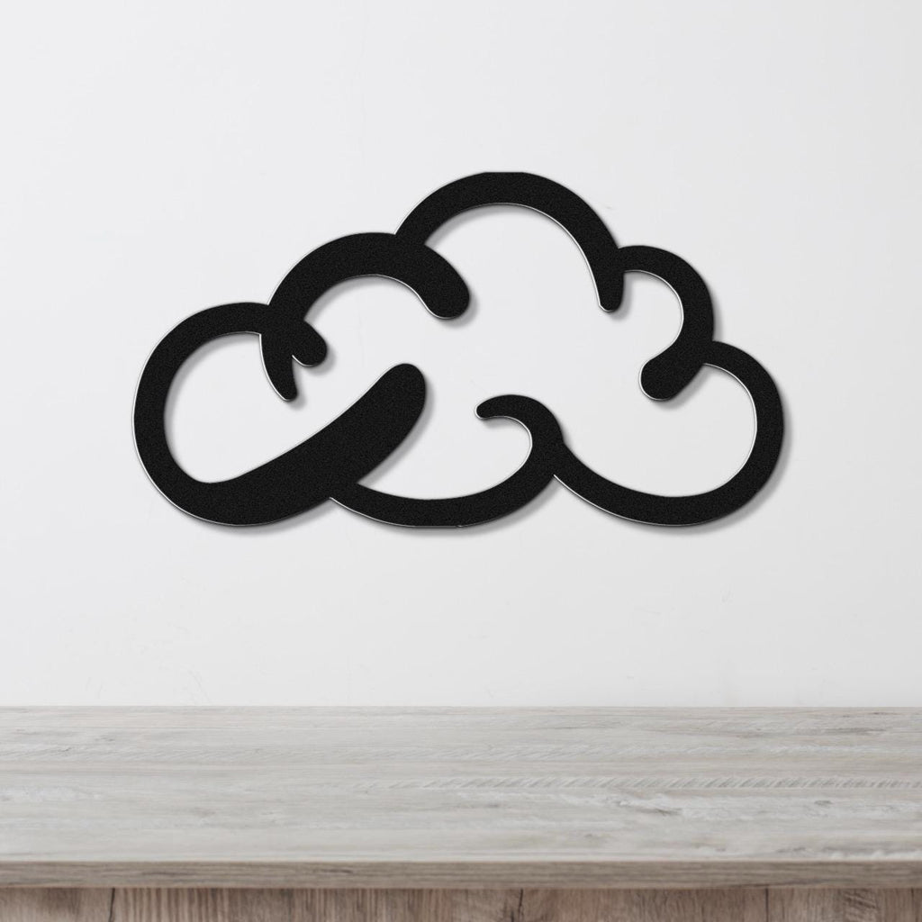 Black metal cloud-shaped wall art with internal cutout details, mounted on a white wall above a light wood surface.