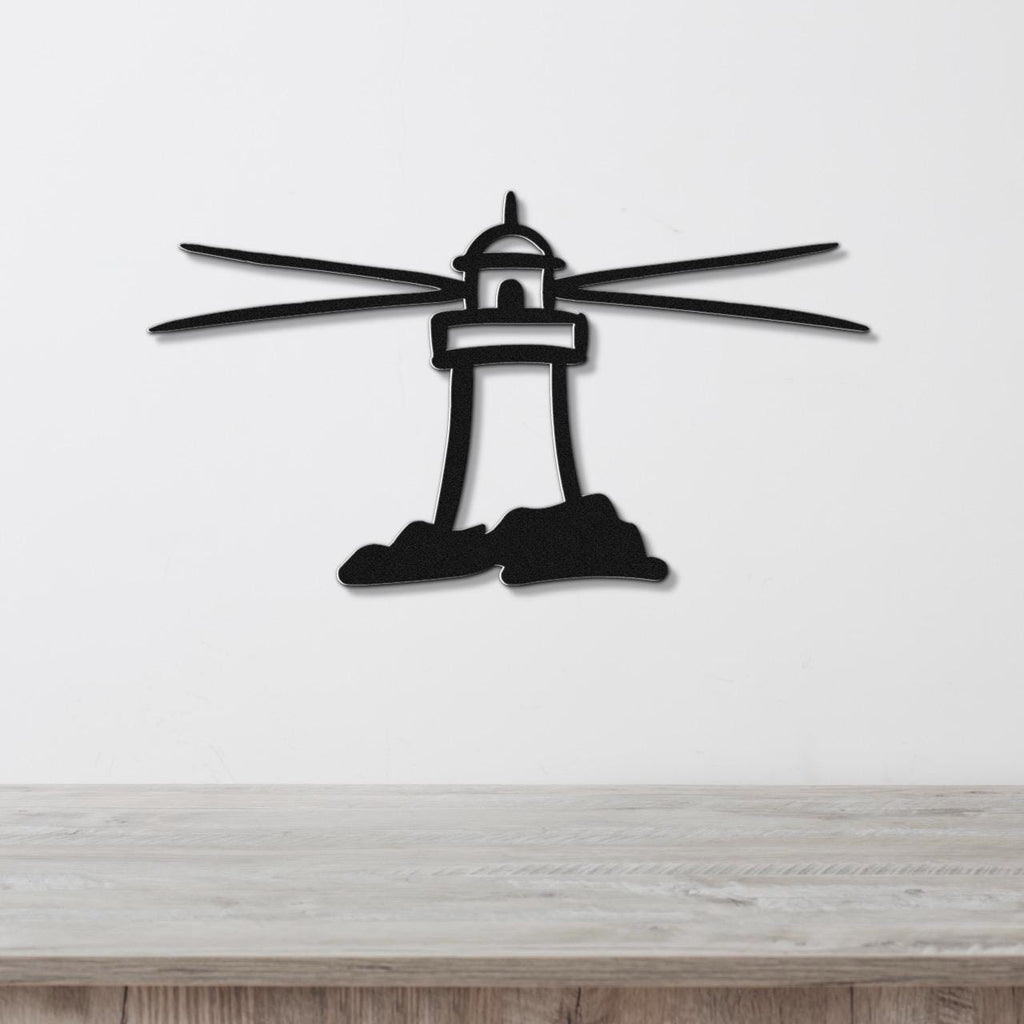 Black metal lighthouse wall art with radiating beam cutouts, mounted on a white wall above a light wood surface.