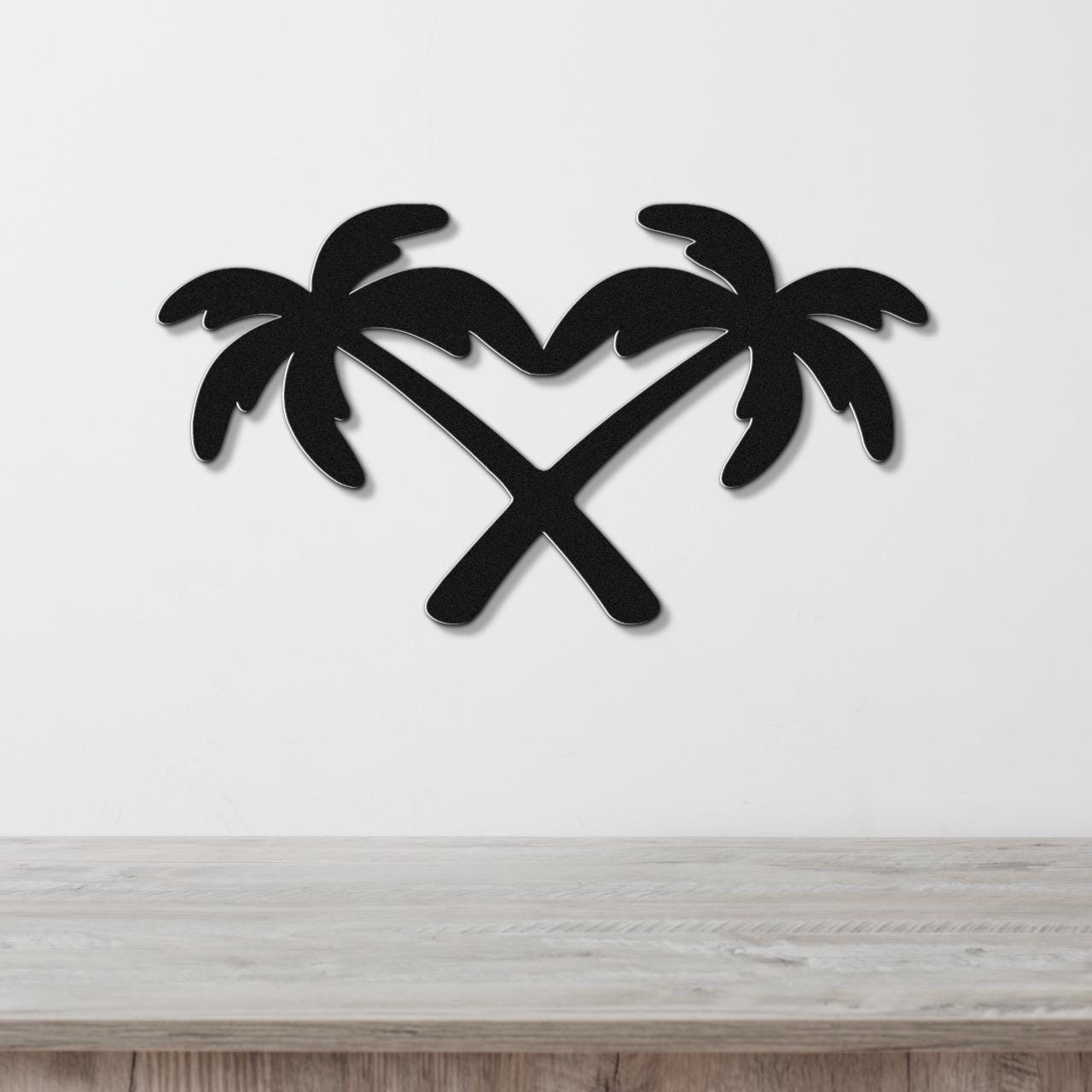Black metal wall art featuring two crossed palm trees forming a heart shape, mounted on a white wall above a wooden surface.