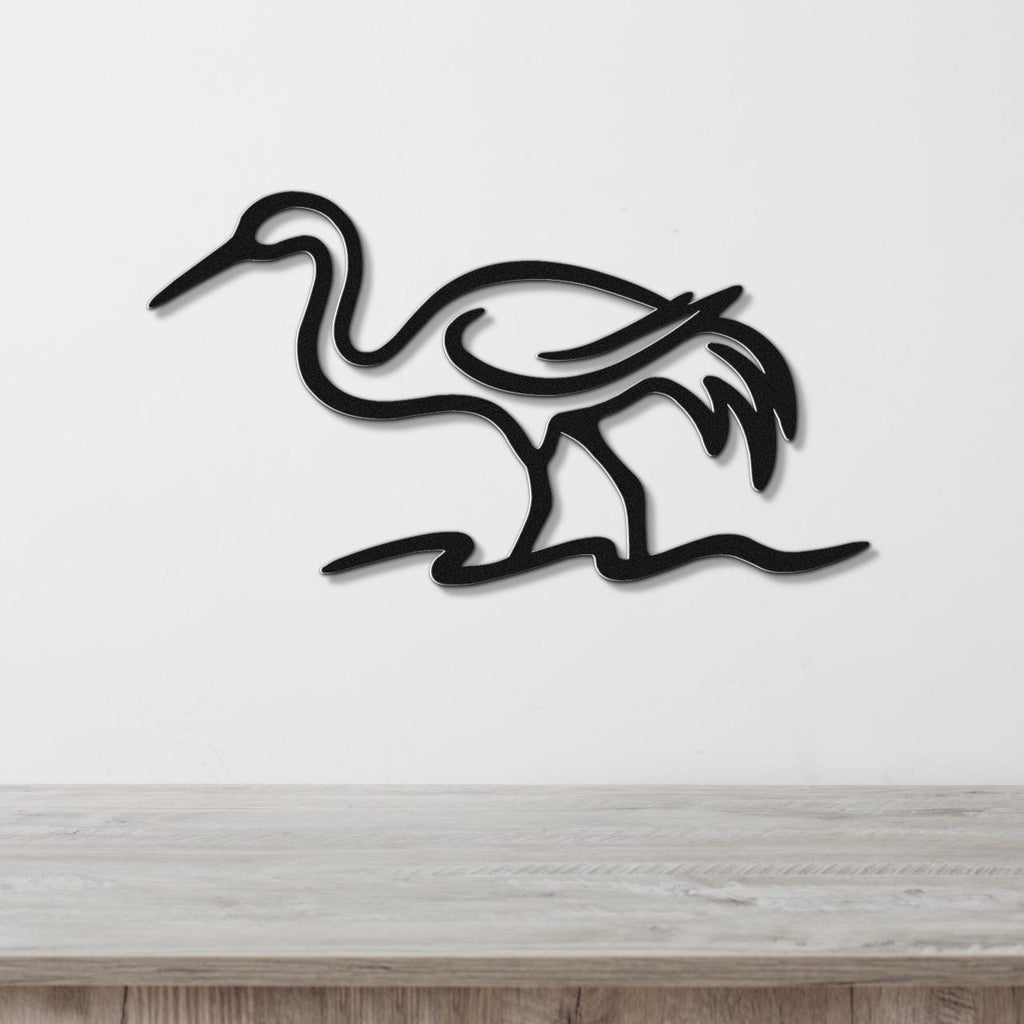 Black metal crane wall art with flowing line cutouts, mounted on a white wall above a light wood surface.