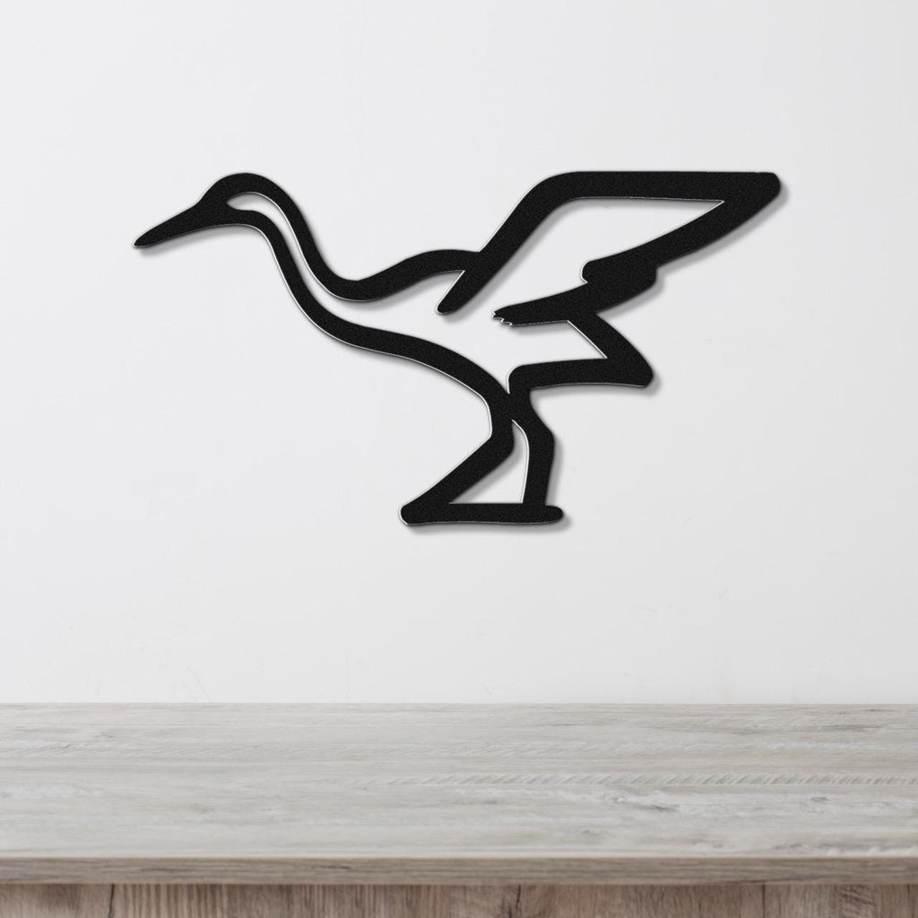 Black metal crane wall art with a minimalist silhouette design, mounted on a white wall above a light wood surface.