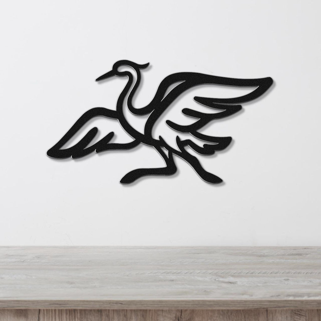 Black metal crane wall art with wing and leg cutouts, mounted on a white wall above a light wood surface.