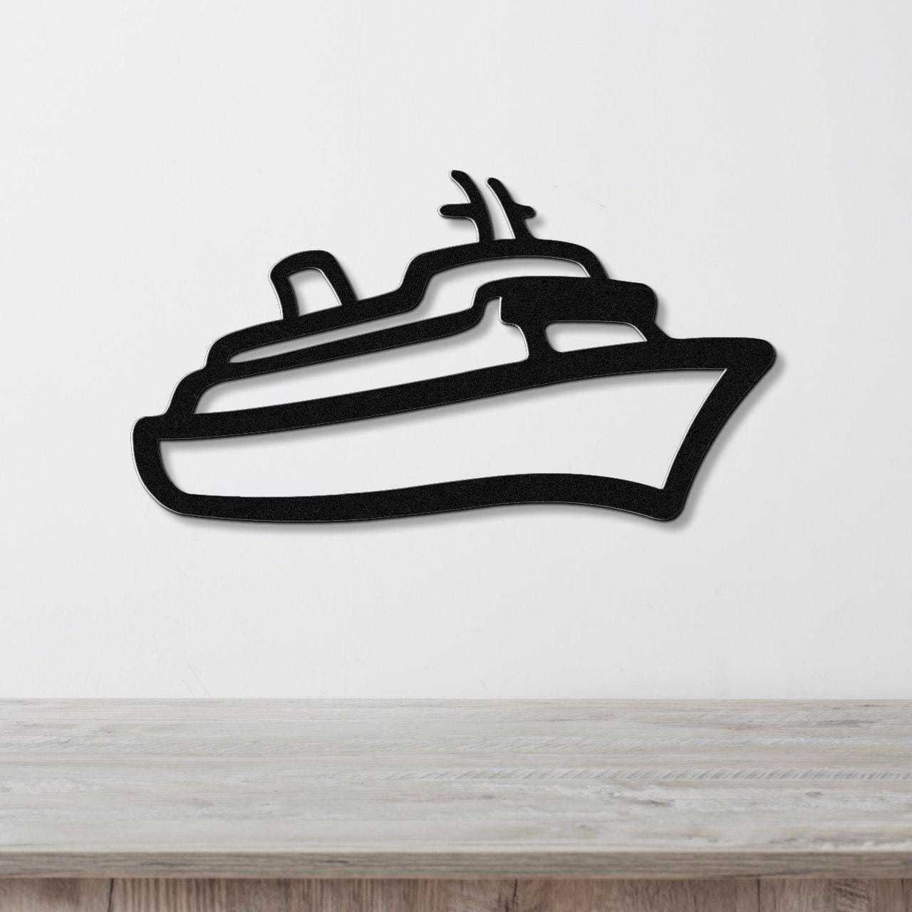 Black metal cruise ship wall art with a silhouette cutout design, mounted on a white wall above a light wood counter.