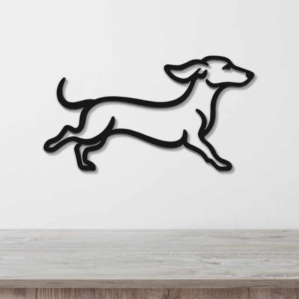 Black metal dachshund wall art in a running silhouette, mounted on a white wall above a light wood counter.
