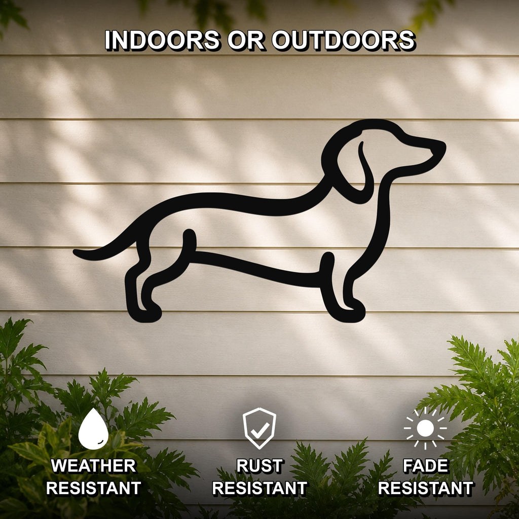 Black metal dachshund silhouette wall art mounted on a light-colored outdoor wall, with green plants at the base and text indicating it is weather, rust, and fade resistant.