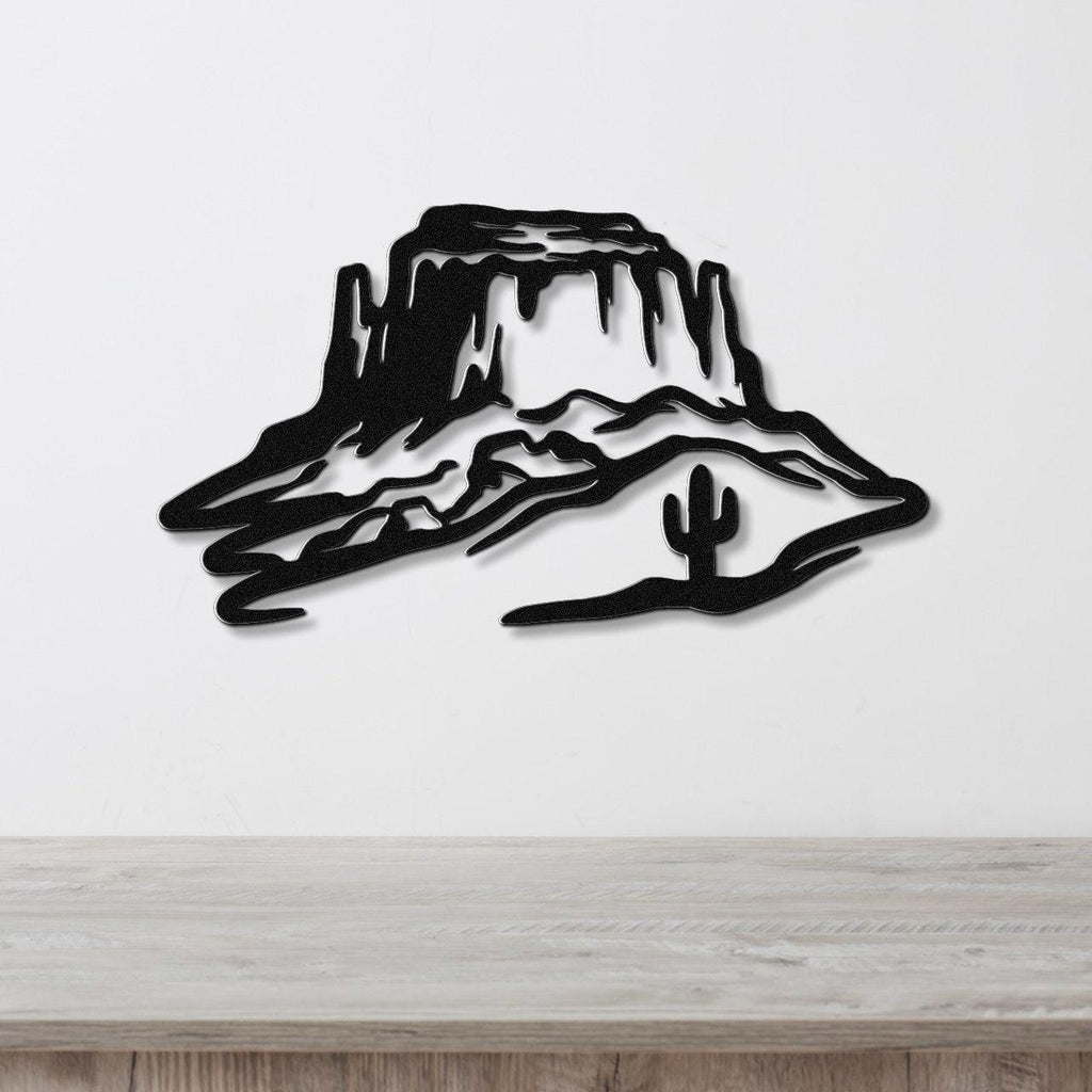 Black metal wall art silhouette of a desert mesa with a saguaro cactus, mounted on a white wall above a wooden counter.