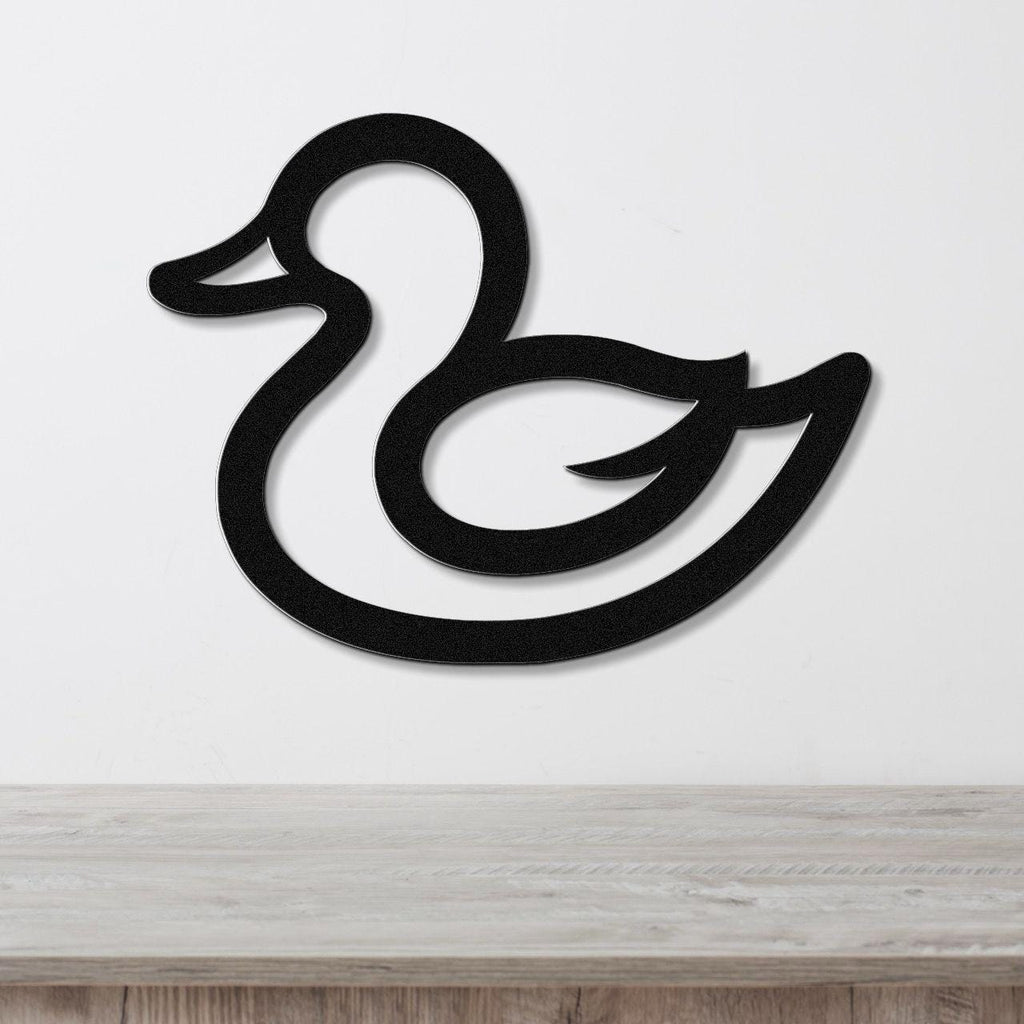 Black metal duck wall art with a silhouette cutout design, mounted on a white wall above a light wood surface.