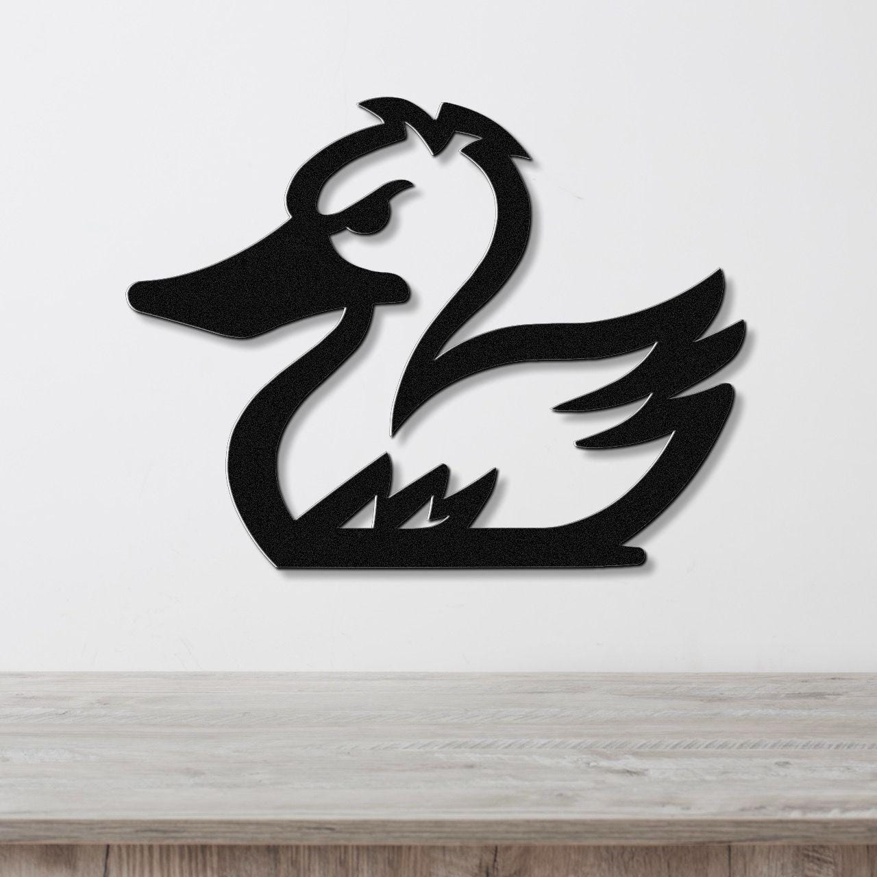 Black metal duck wall art silhouette with cutout details, mounted on a white wall above a light wood surface.