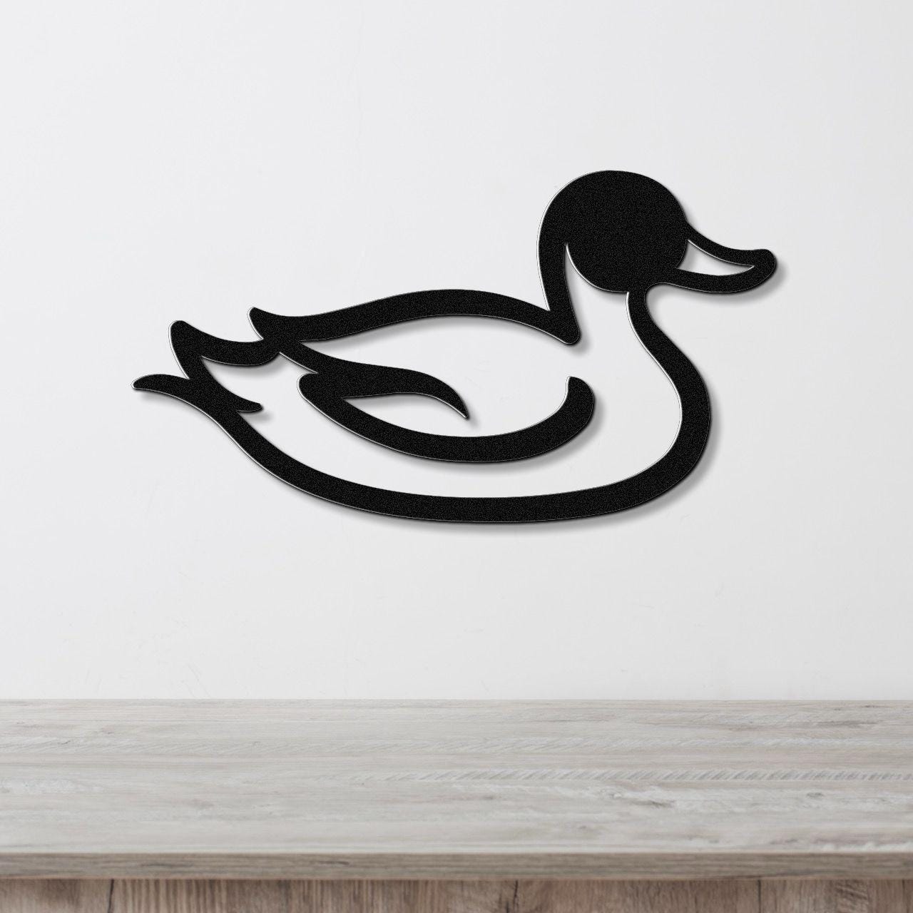 Black metal duck wall art with a silhouette cutout design, mounted on a white wall above a light wood countertop.