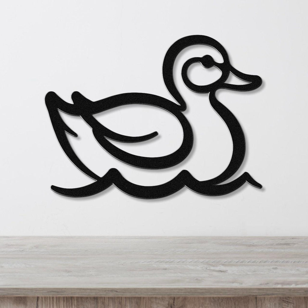 Black metal duck wall art with a silhouette design, mounted on a white wall above a light wood surface.