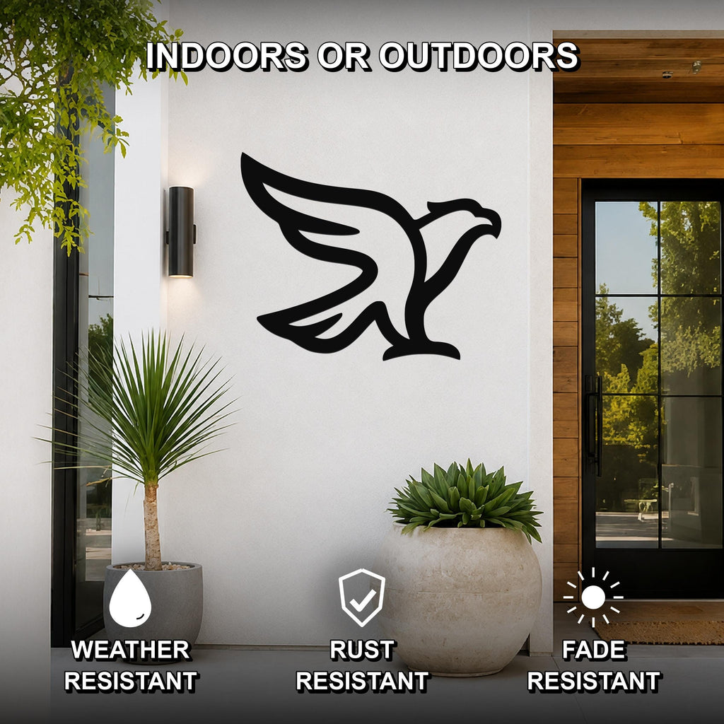 Black metal eagle wall art silhouette with outstretched wings, mounted on a white exterior wall beside a glass door and potted plants.