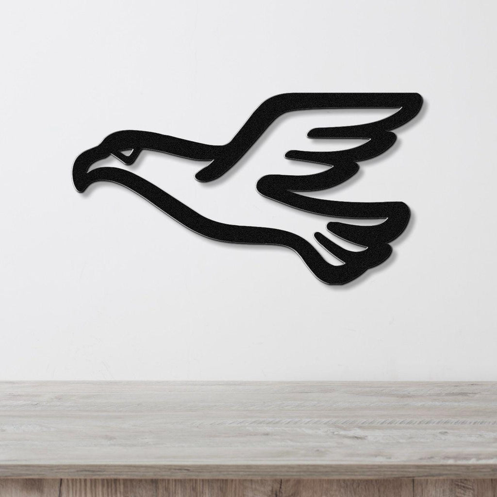 Black metal eagle wall art with a soaring silhouette and cutout wing details, mounted on a white wall above a light wood counter.