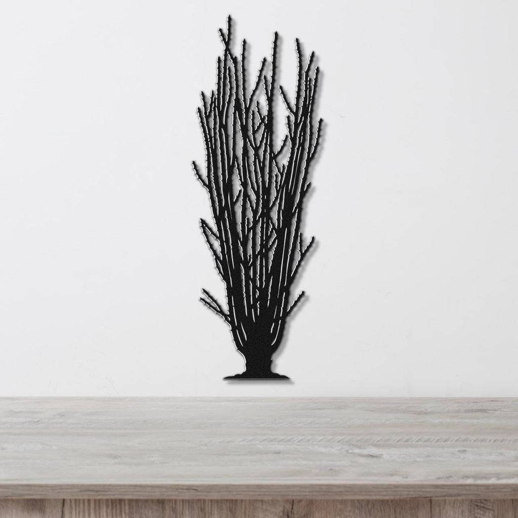 Black metal wall art cutout of a tall ocotillo plant with branching stems, mounted on a white wall above a light wood surface.