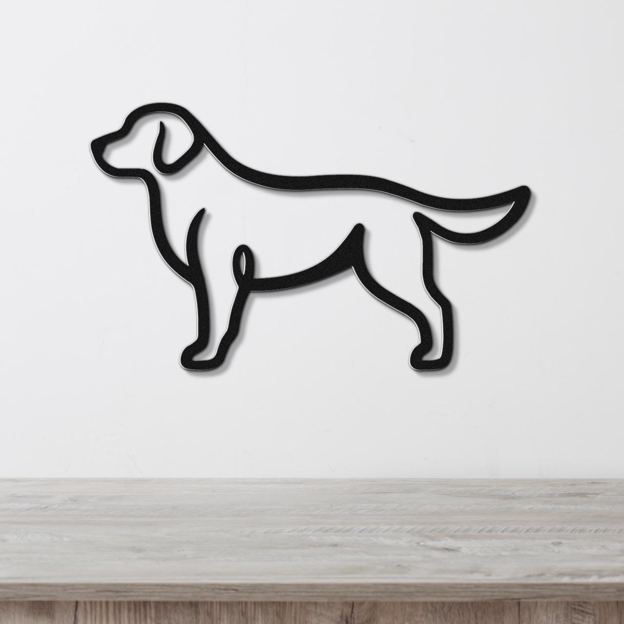 Black metal wall art in a bold silhouette of a standing dog, mounted on a white wall above a light wood surface.