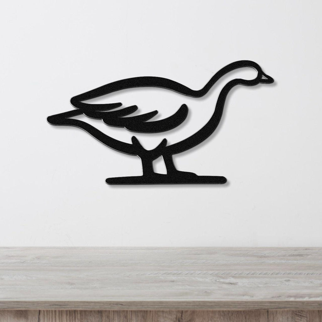 Black metal goose wall art silhouette with internal cutout details, mounted on a white wall above a light wood countertop.