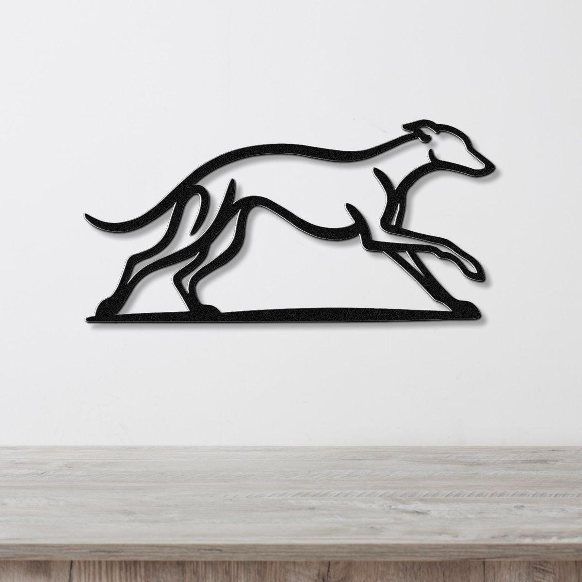 Black metal greyhound wall art with motion-line cutouts, mounted on a white wall above a light wood counter.