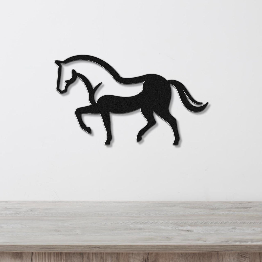 Black metal horse wall art with a silhouette design, mounted on a white wall above a wooden surface.