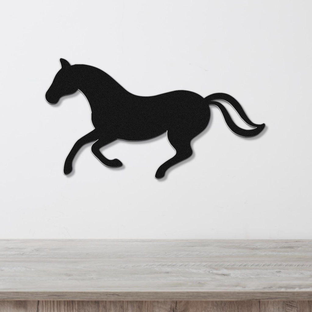 Black metal horse wall art silhouette in a running pose, mounted on a white wall above a light wood surface.
