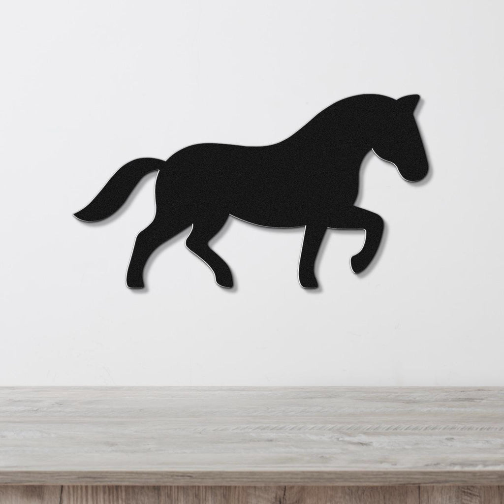 Black metal horse wall art silhouette in a walking pose, mounted on a white wall above a light wood surface.