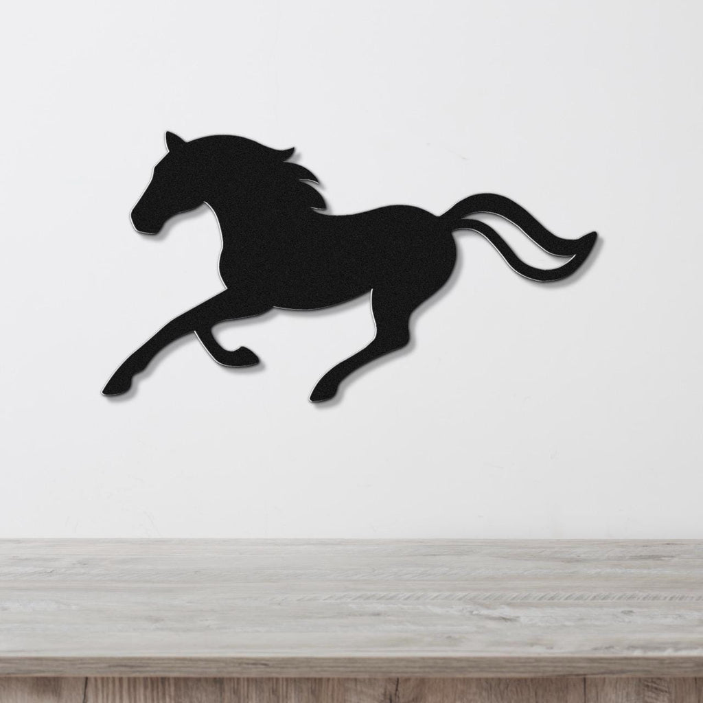 Black metal horse wall art silhouette in a running pose, mounted on a white wall above a light wood surface.