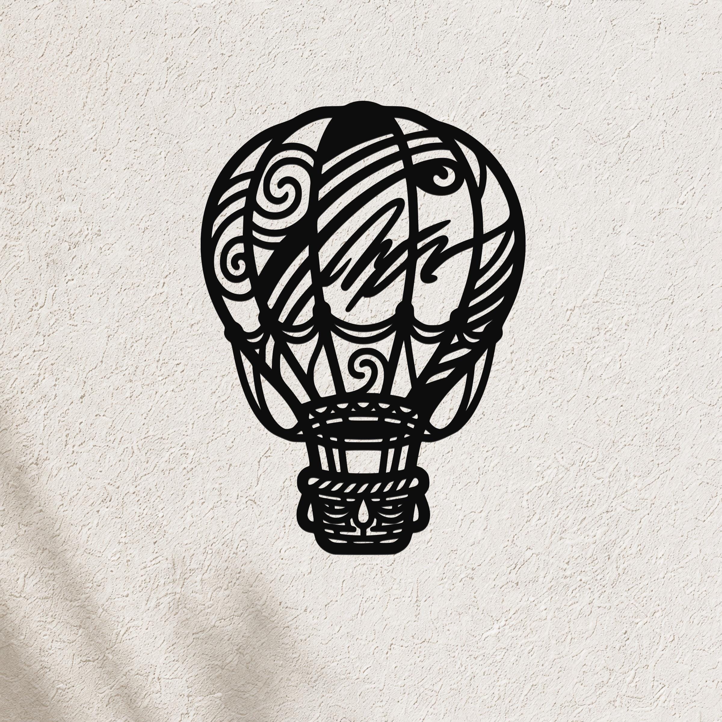 Black metal wall art cutout of a hot air balloon with intricate swirl and geometric patterns, mounted on a textured white wall.
