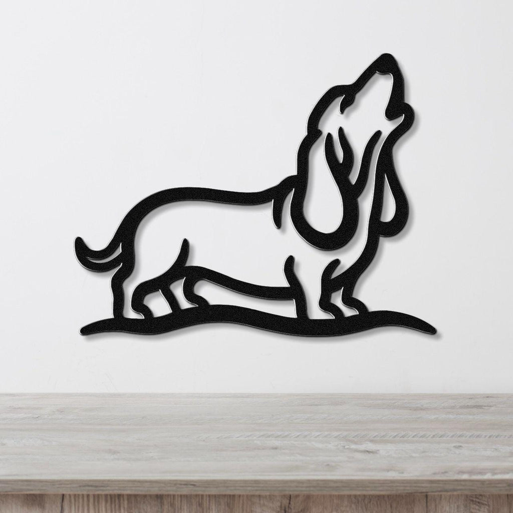 Black metal wall art of a howling basset hound in a bold silhouette, mounted on a white wall above a light wood surface.