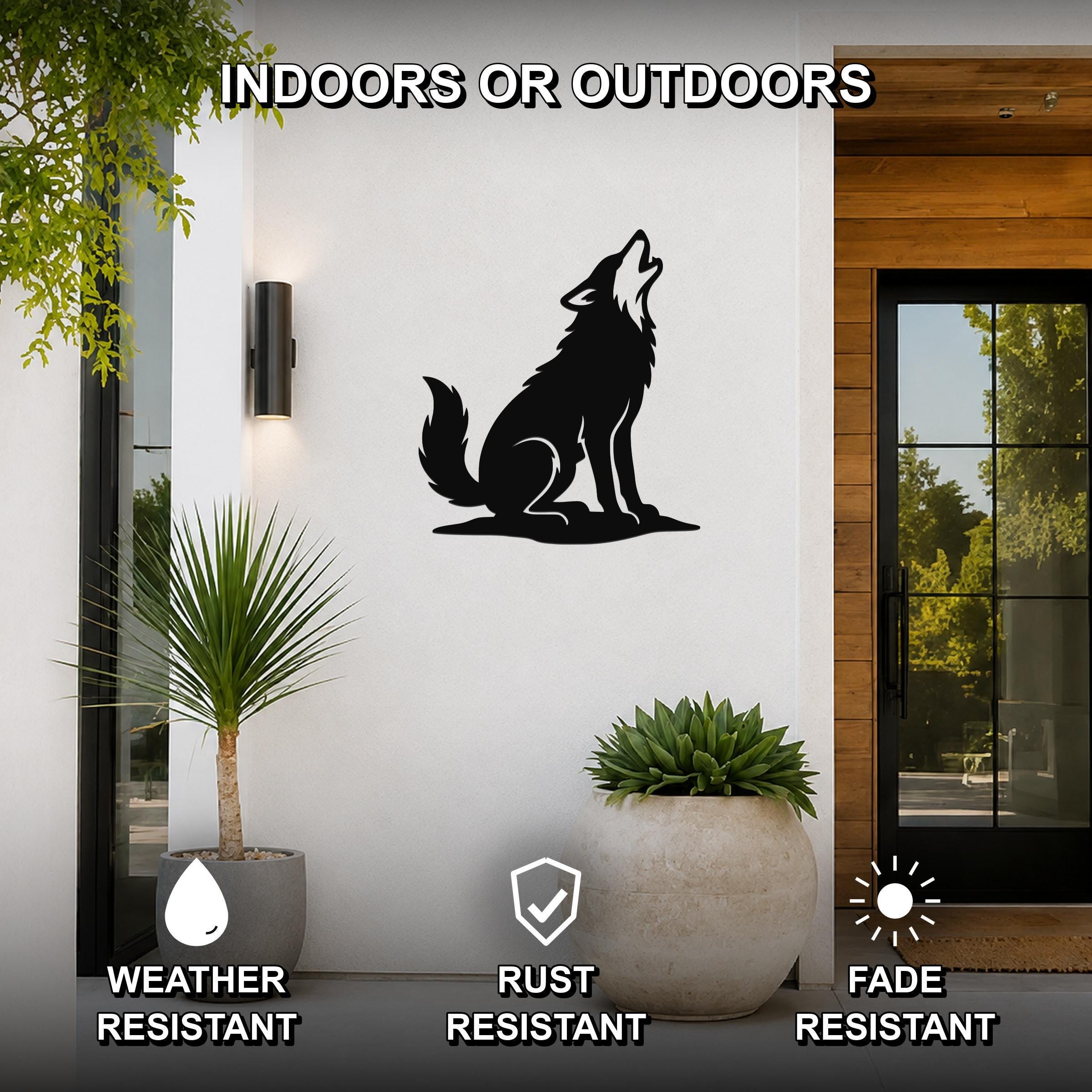 Black metal coyote wall art in a howling silhouette, mounted on a white exterior wall beside a glass door and potted plants, with text indicating indoor or outdoor use and weather, rust, and fade resistance.