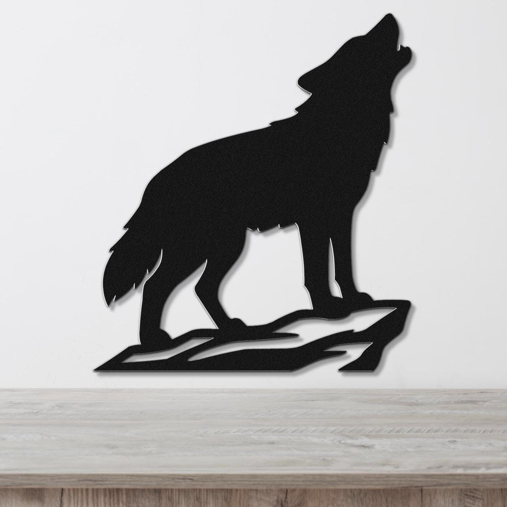 Black metal wall art silhouette of a howling coyote on a rock, mounted on a white wall above a wooden surface.