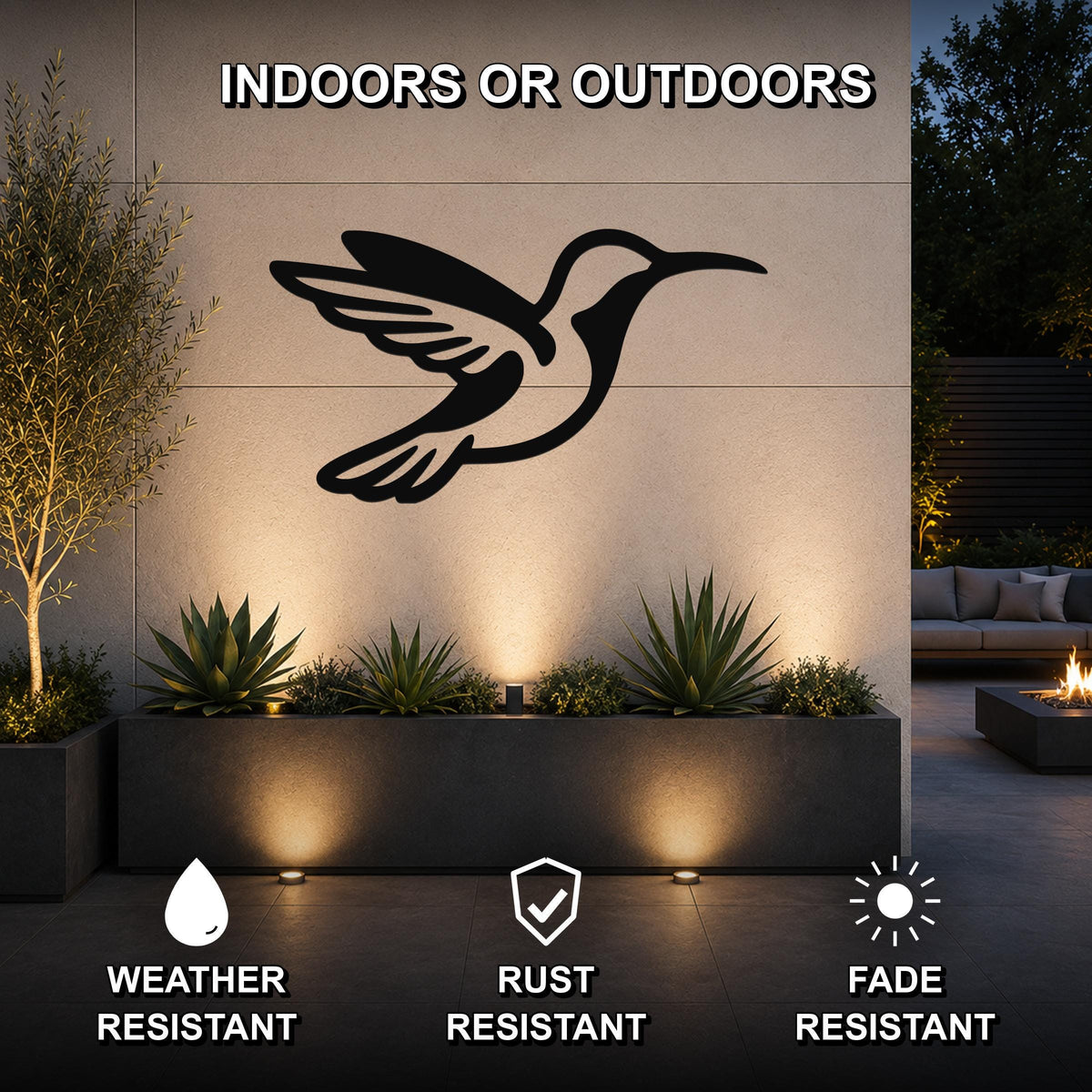 Black metal hummingbird wall art with wing and tail cutouts, mounted on an outdoor wall above a planter in a patio setting.